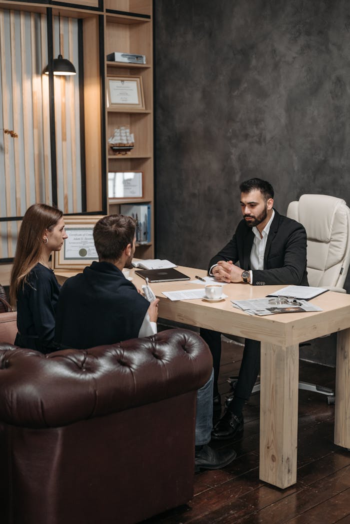 services-01 A professional business meeting with three people discussing documents in an office setting.